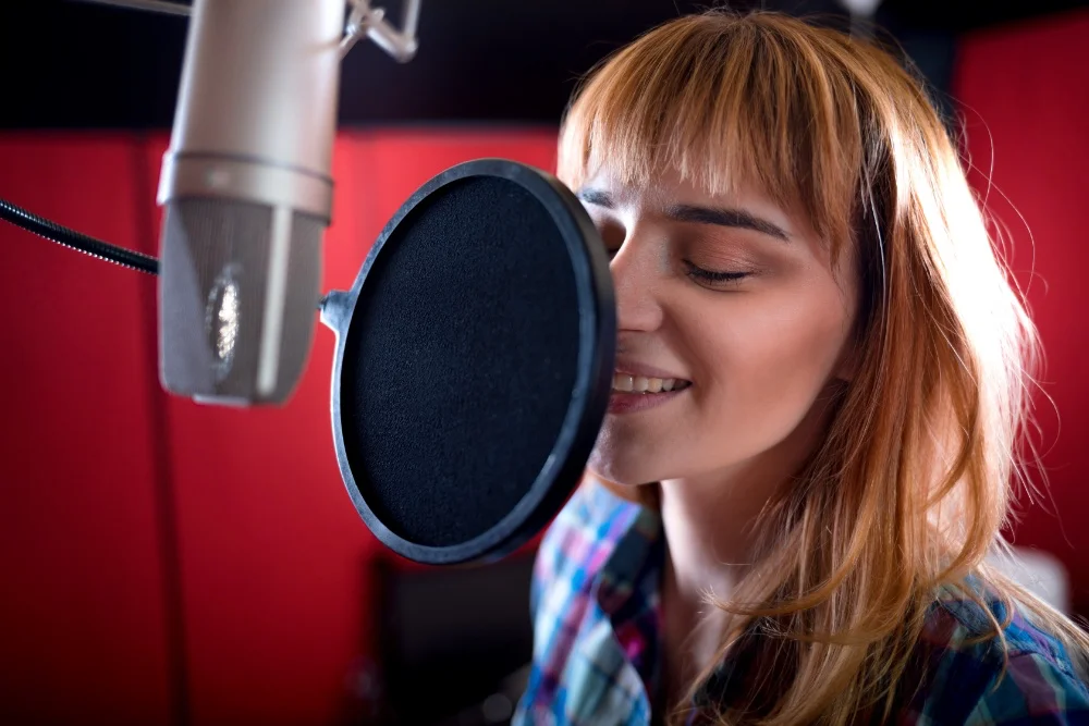 A woman singing into a microphone in a recording studio, achieving the Perfect Sound.
