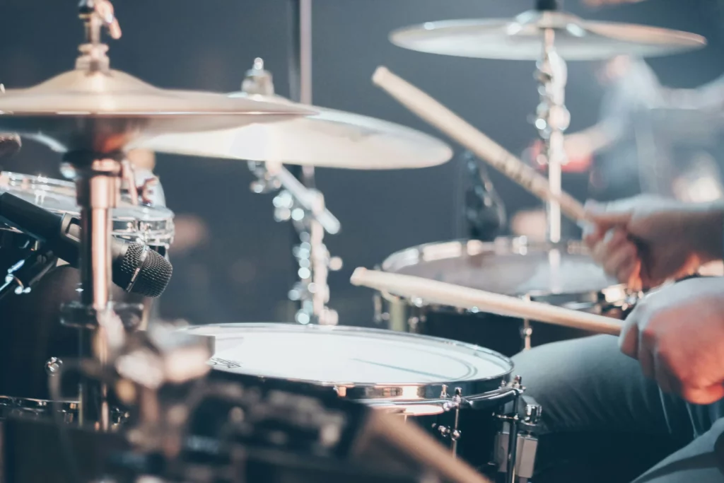 a man playing drums with a microphone together with cymbals